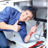 Mature plumber fixing a sink at kitchen